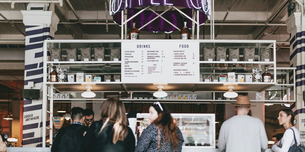 group of people standing in front of food stall counter