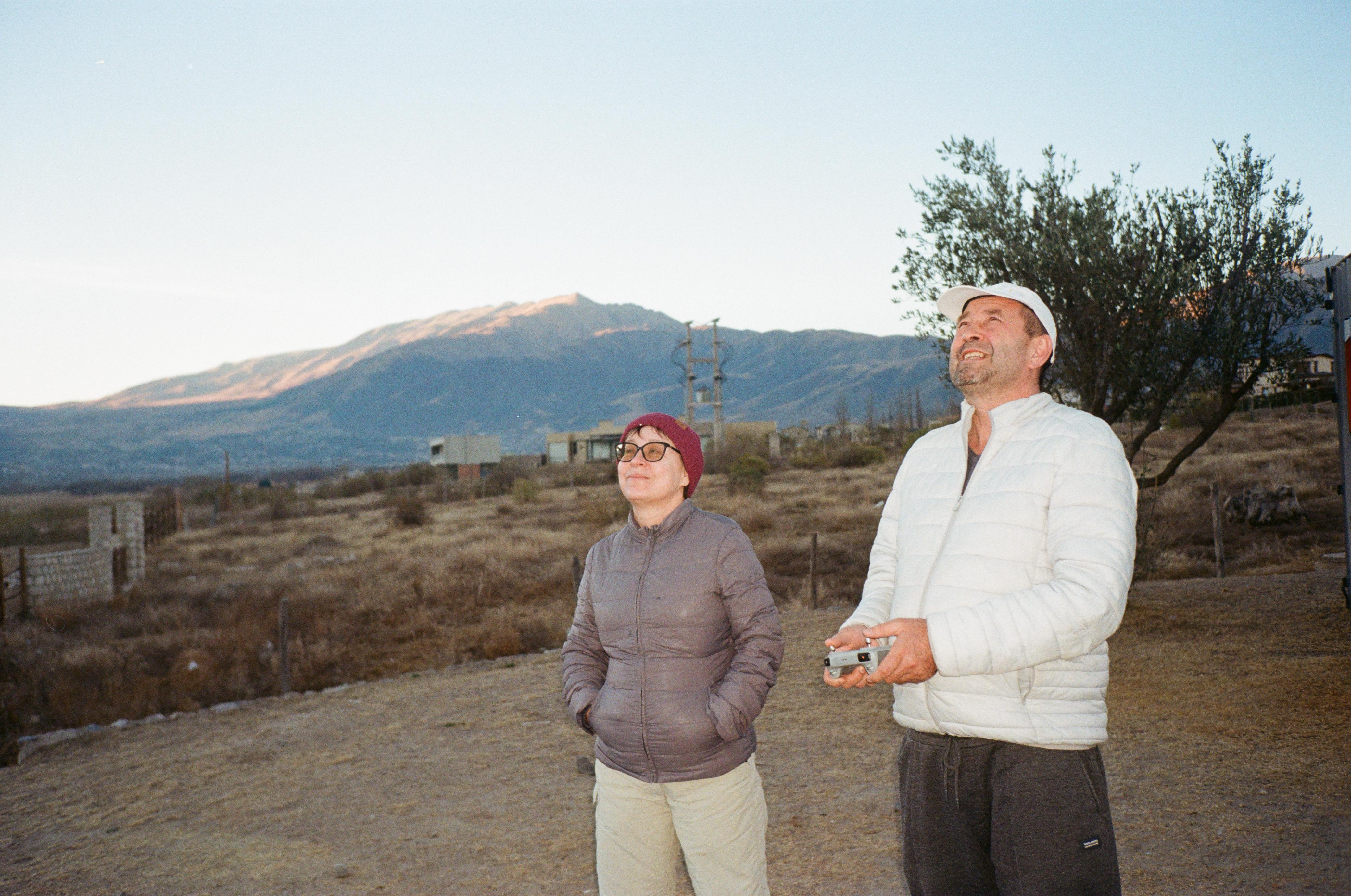 Mujer sentada sobre un tronco frente a una cascada doble en un bosque frondoso de Argentina.