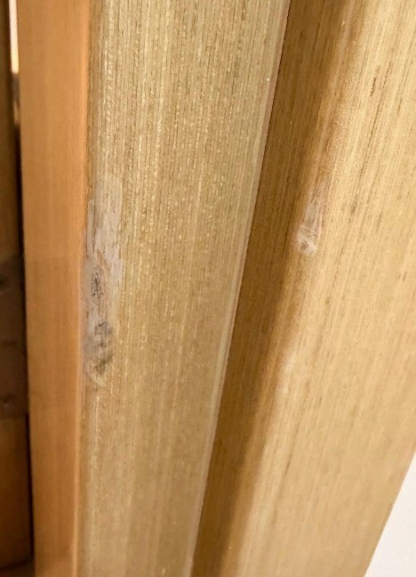 Gouged and scuffed natural oak door frame before repair in Dubai