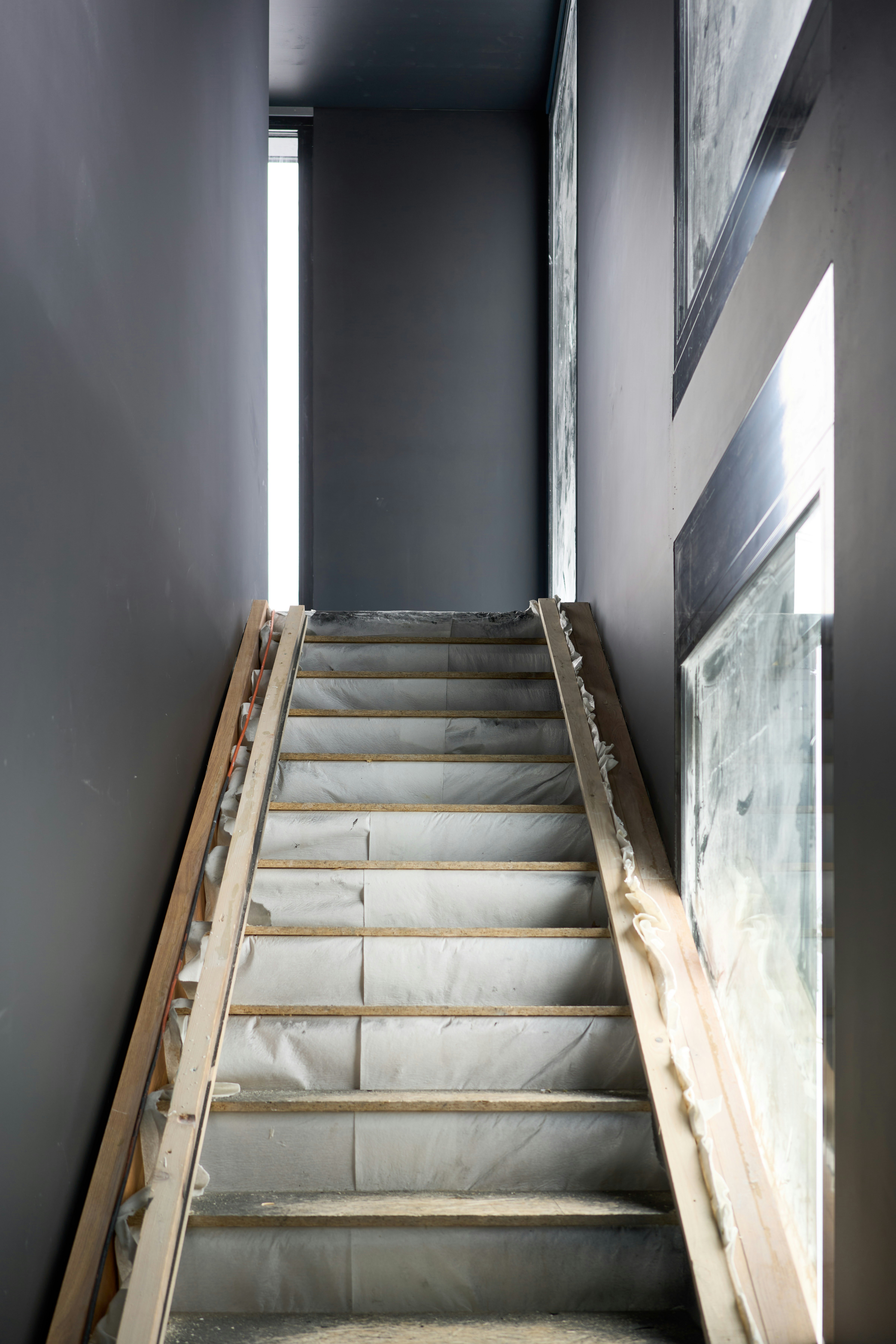 A wooden staircase under construction with gray walls.