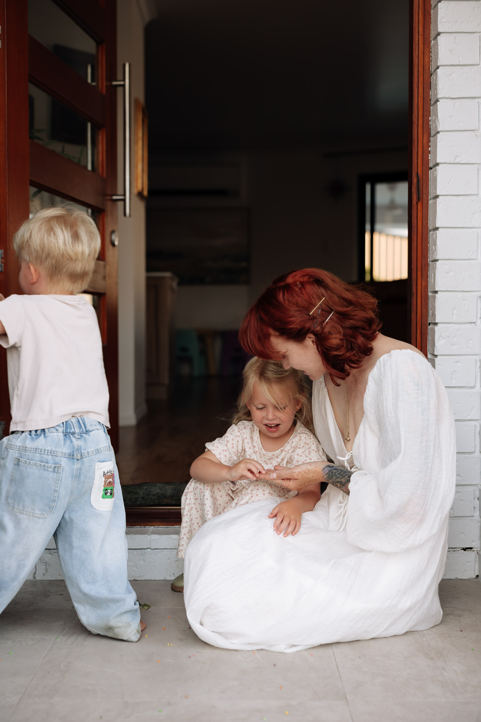 Siblings gathered at entrance of home with mum, captured in relaxed motherhood session
