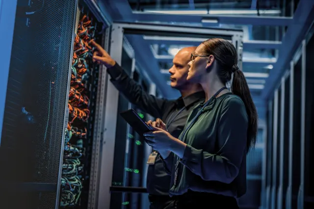 Técnicos revisando el cableado de un servidor en un centro de datos, la infraestructura que protege el seguro Allianz Cyber frente a ciberataques y brechas de seguridad