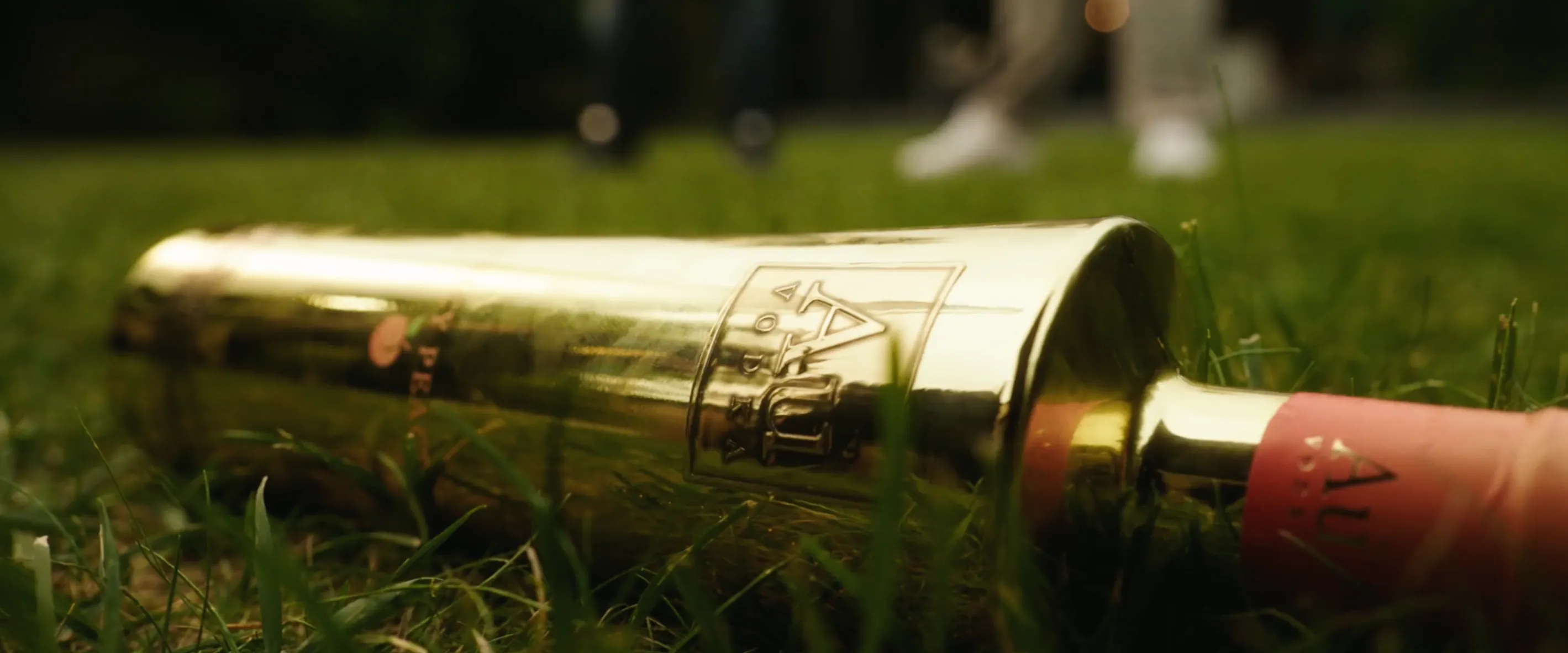 A bottle of AU Vodka lying down on grass