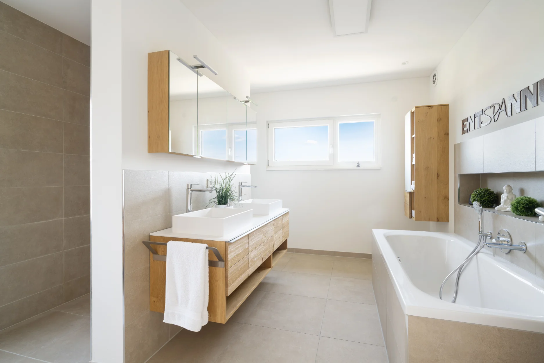 Modernes Badezimmer mit Doppelwaschbecken aus Keramik, freistehender Badewanne und Holzelementen an der Wand inkl. Duschbereich mit Glaswand und Hängeaufbewahrung.