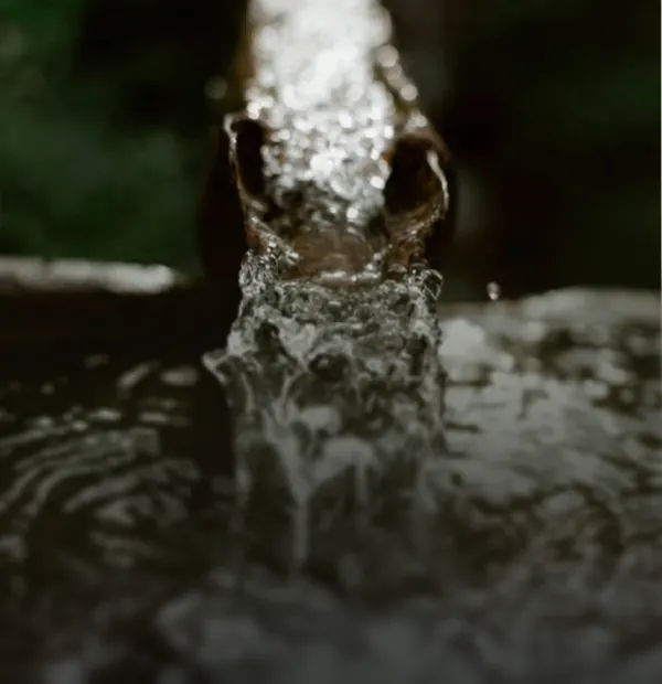 Primer plano de un chorro de agua cristalina fluyendo a alta presión, representando el servicio de perforación y llenado rápido para piscinas.