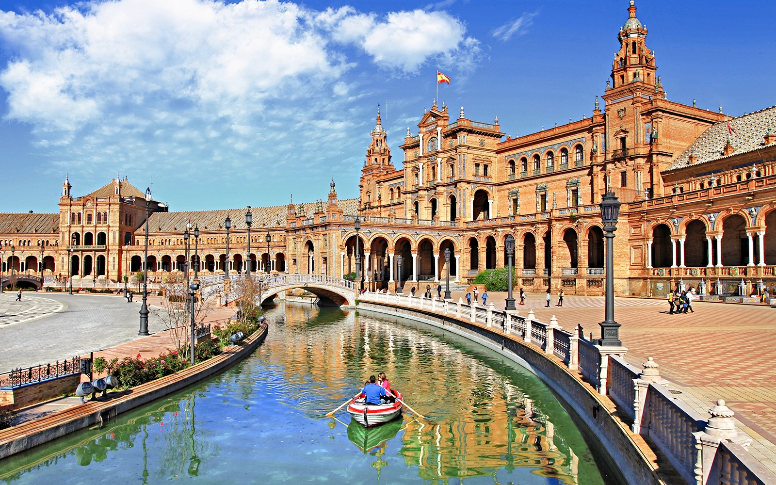 Roeiboot op het kanaal bij Plaza de España, Sevilla, met een historisch gebouw op de achtergrond.