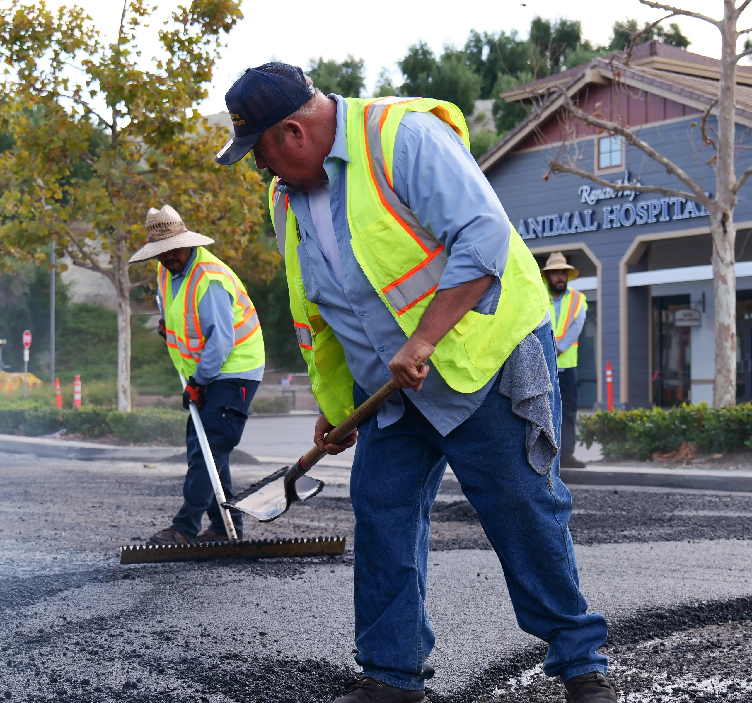 Asphalt crew member raking new pavement