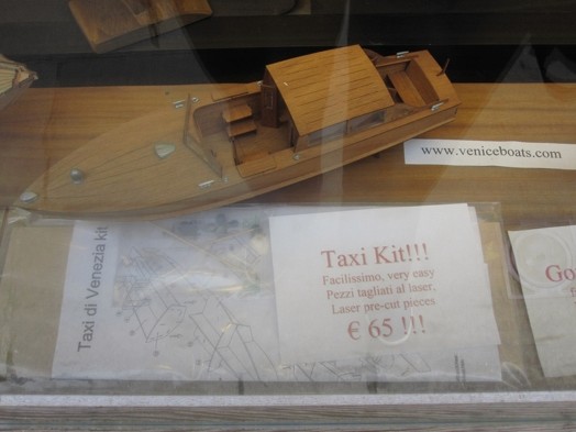 A photo of miniature wood boat alongside plans on how to ensemble it.