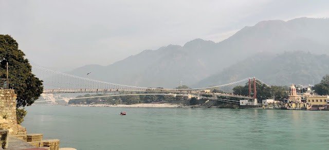 Ram jhula standing across the Ganges with mountains in the background.