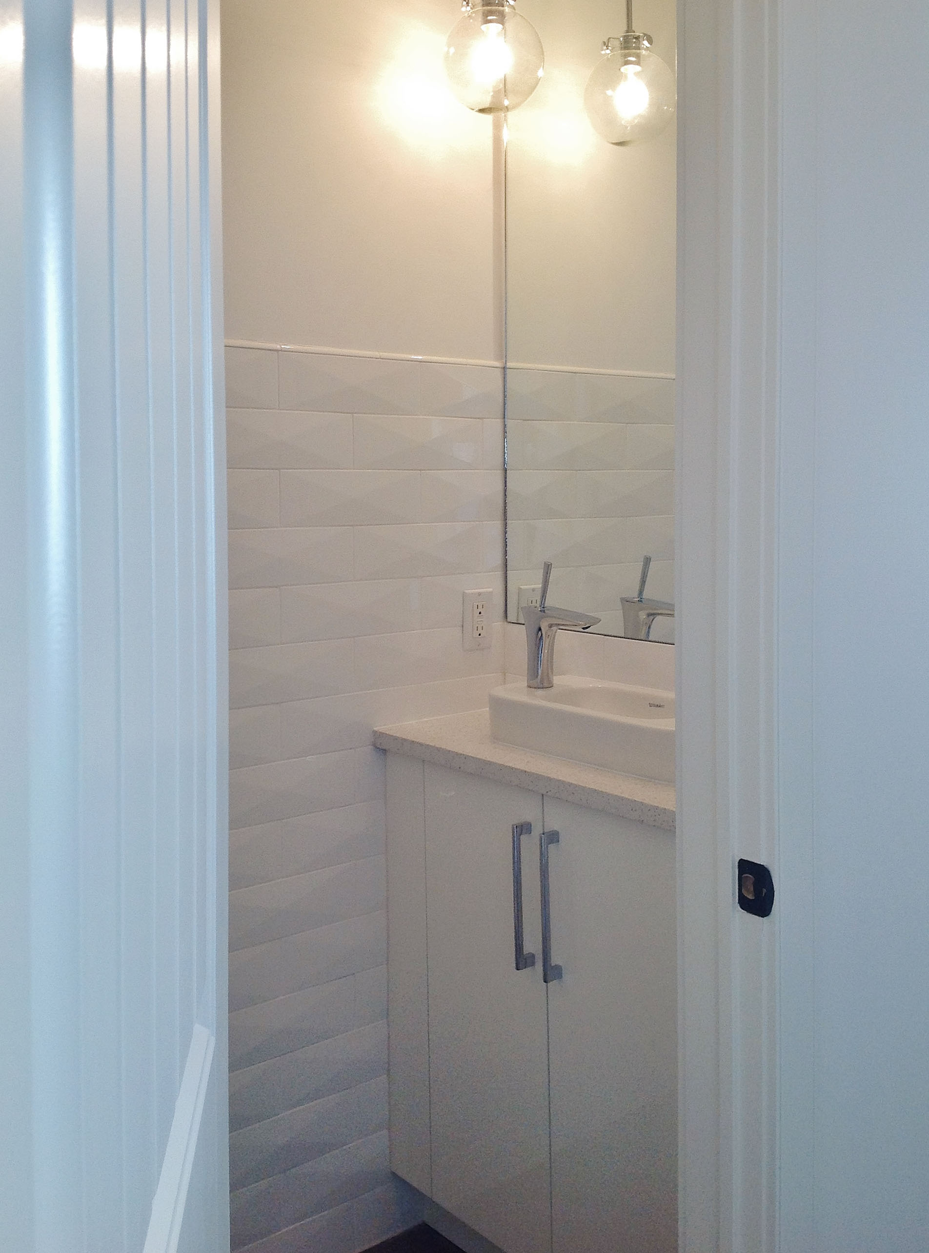 Image of KHD Homes bathroom design with white cabinets, tile backsplash, and modern sink and lighting fixtures installed.