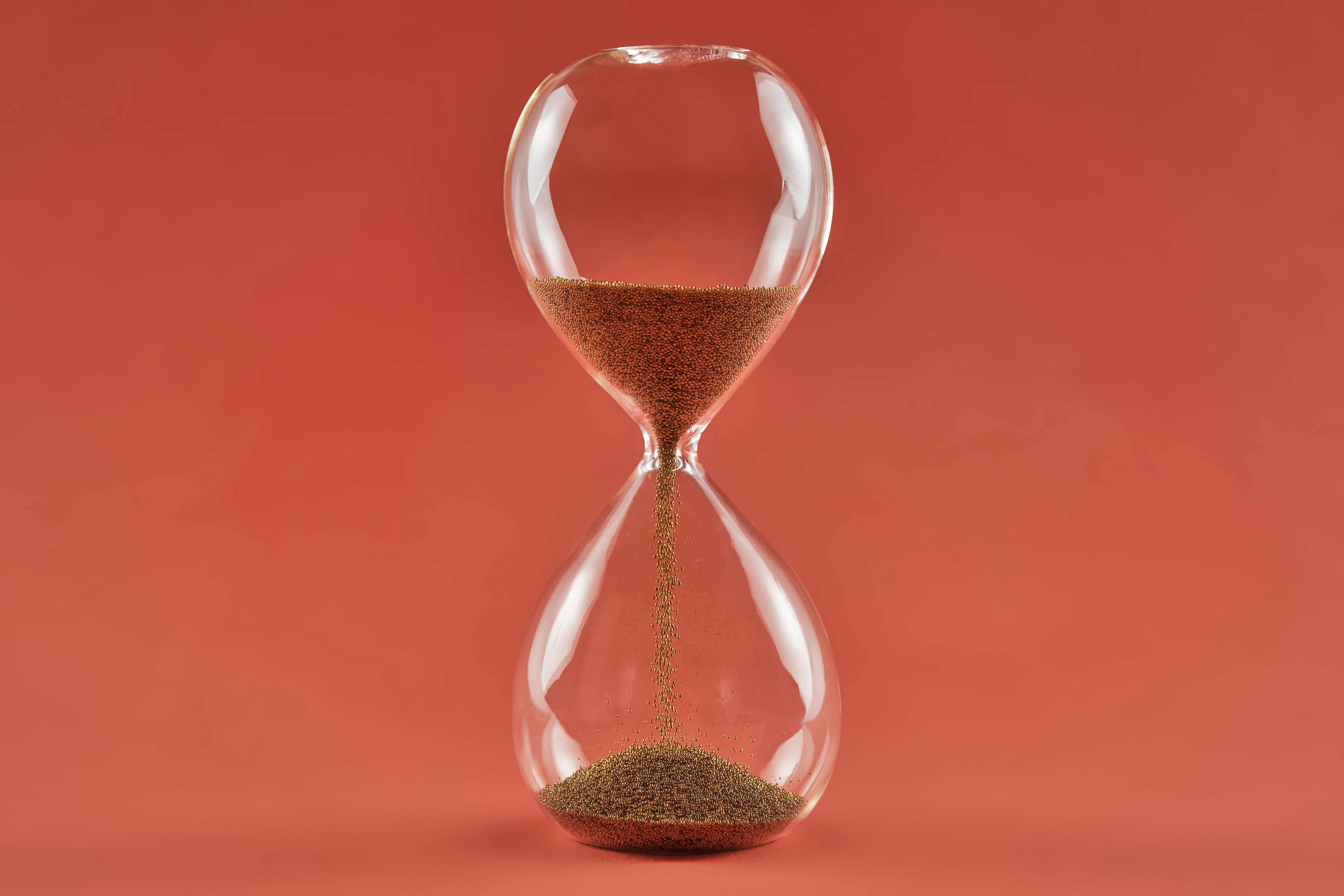 a red background to an hourglass with sand running out