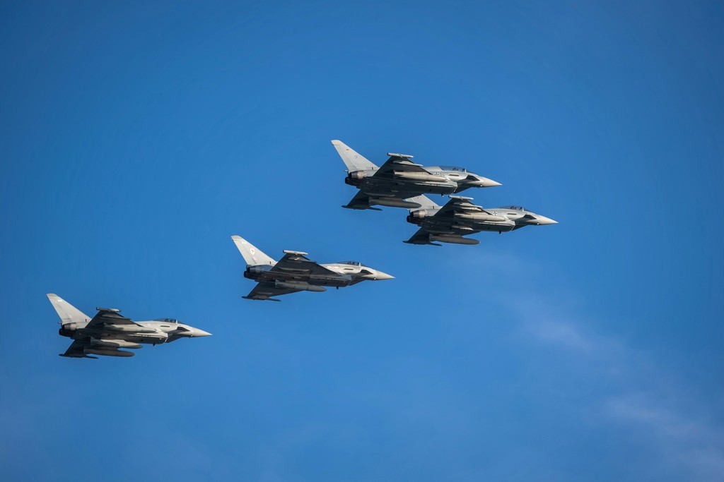 a group of fighter jets flying through a blue sky