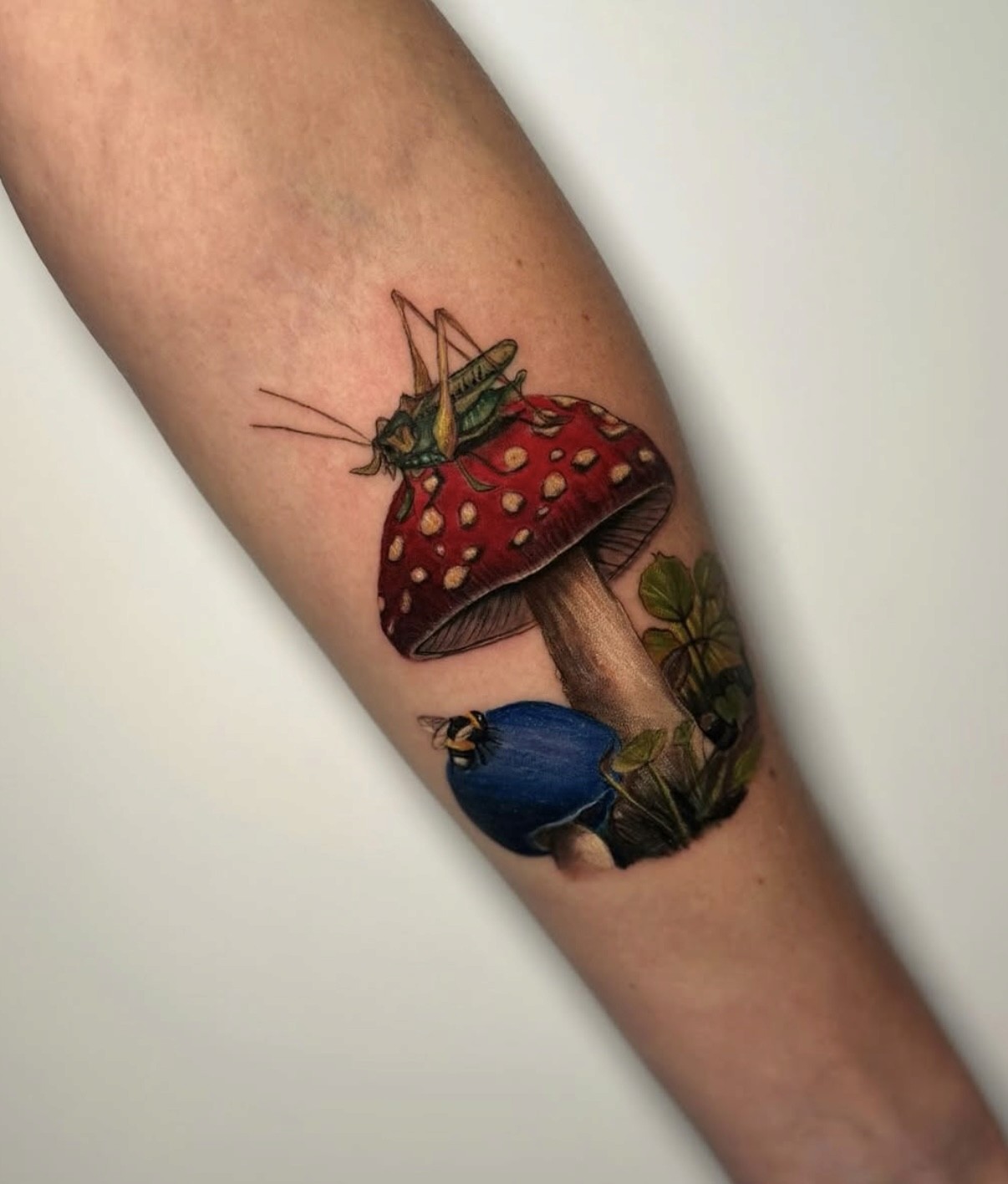 A vibrant tattoo of a chainsaw-like creature on a person's forearm. The tattoo is detailed with shades of orange, black, teal, and red.