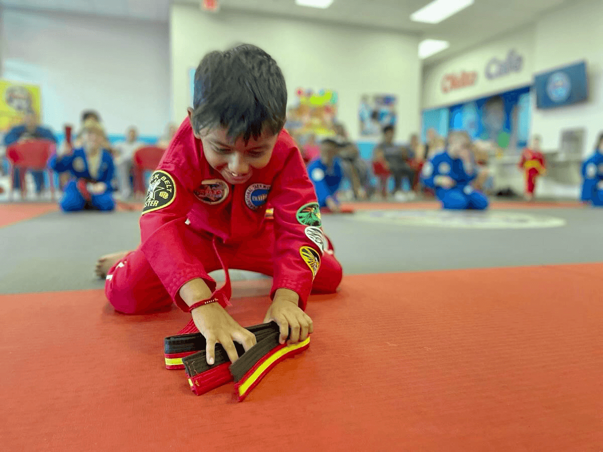 Happy child grabbing his new belt after graduation.
