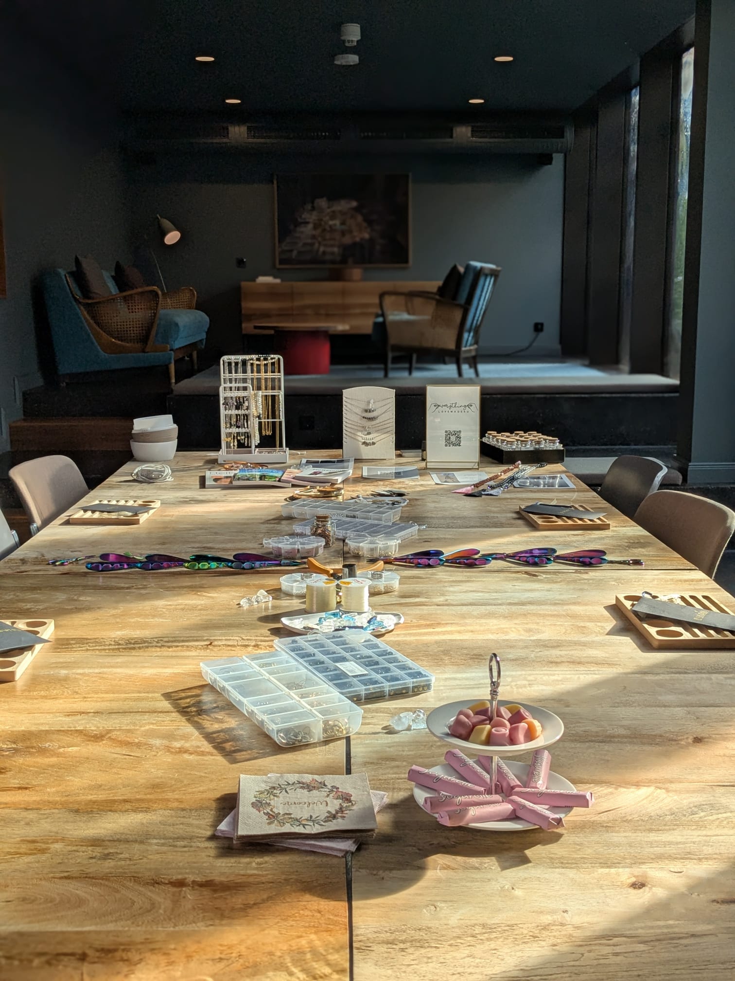 A serene and elegant spa space with wooden reclining chairs and white cushions. Golden sunlight filters through a cascading water feature, creating a peaceful atmosphere. Tropical plants and candles add to the relaxing ambiance.