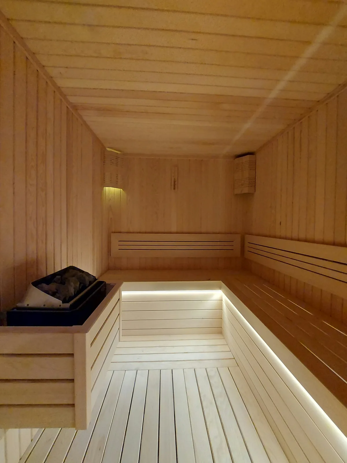 An empty wooden sauna with softly lit benches