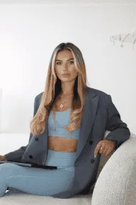 Woman reading a book surrounded by lush green plants.