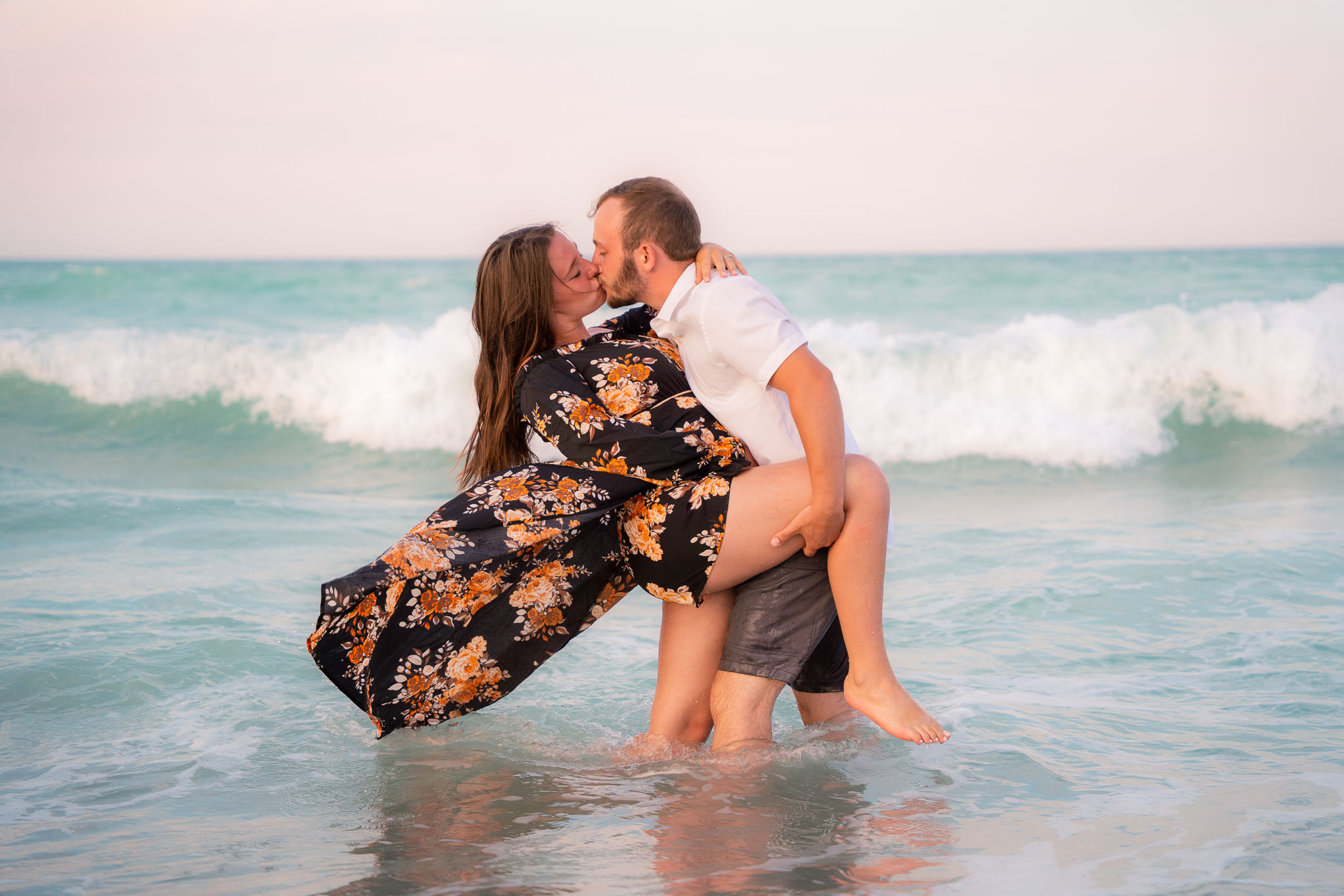  a couple embracing for a kiss while standing in the ocean wave