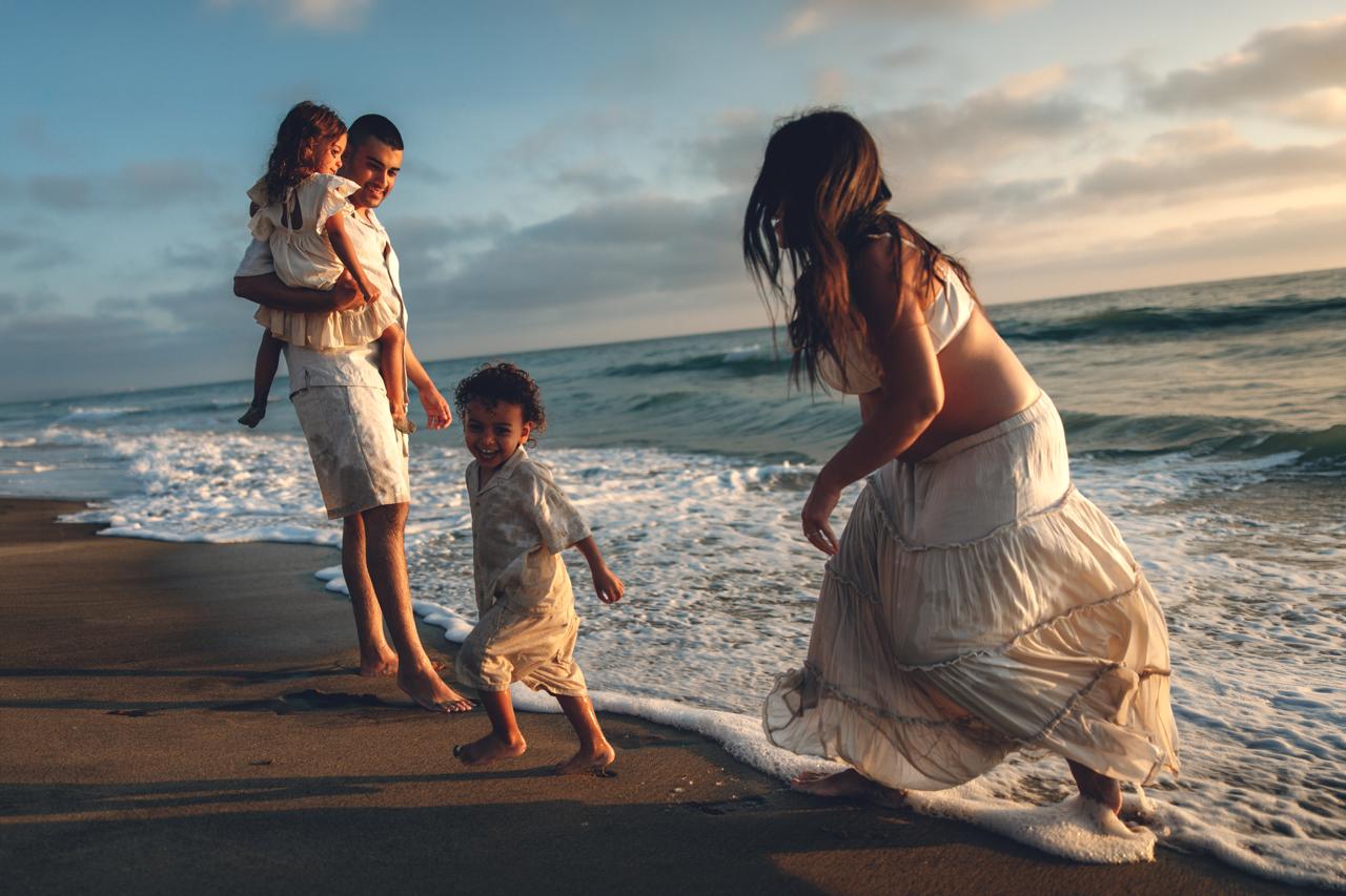 Family walking along the shoreline at dusk, kids running ahead near the waves