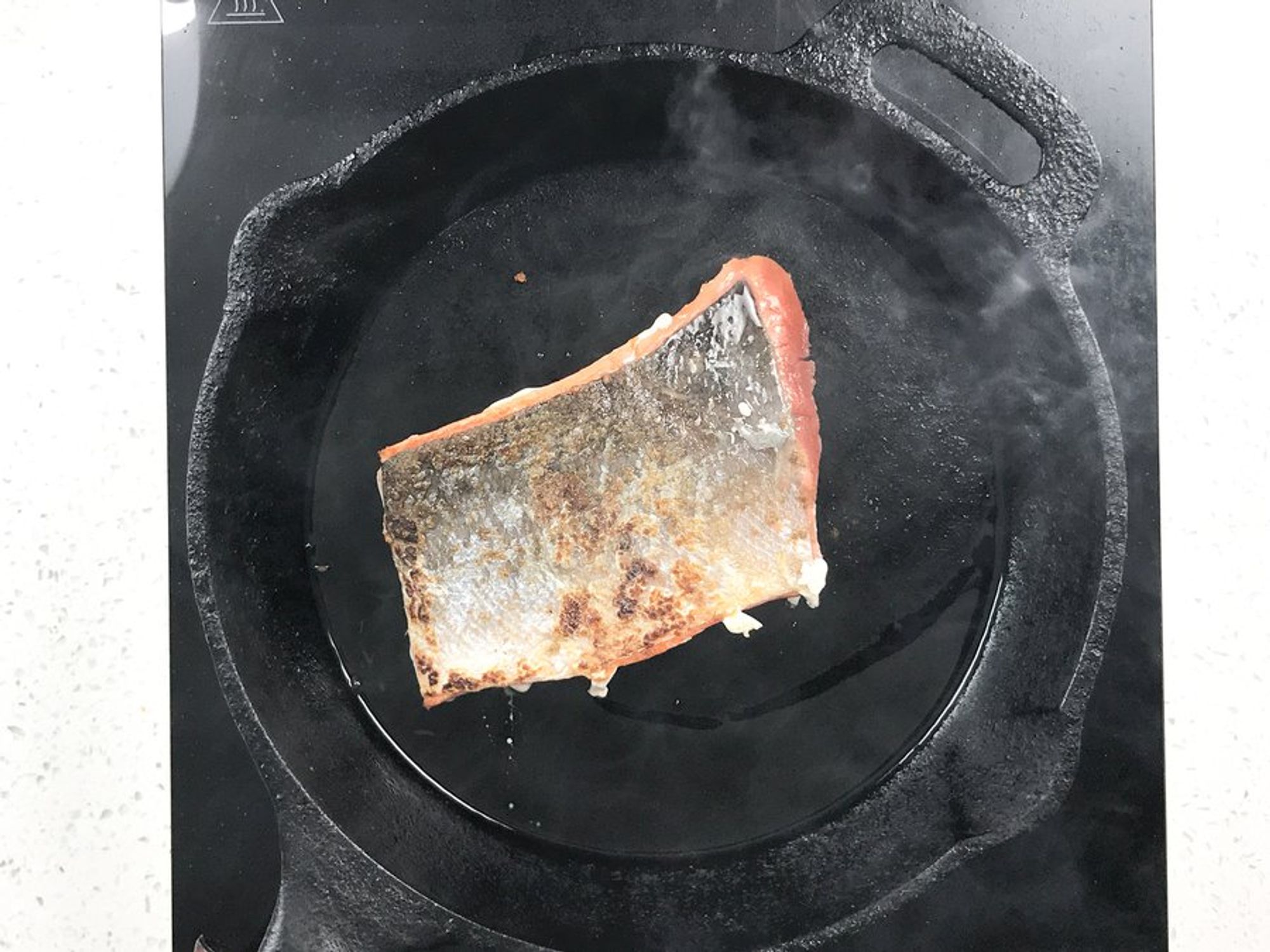 a salmon fillet being cooked in a heavy skillet