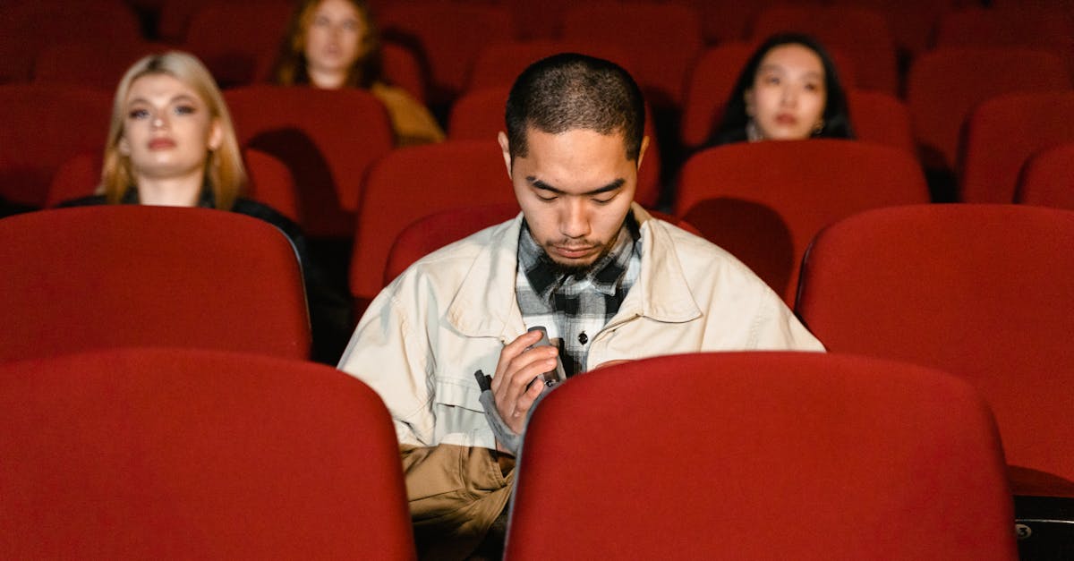 A diverse group seated in a movie theater, watching seriously.