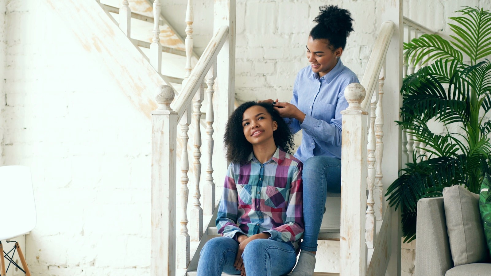 Mother styling her daughter's hair on stairs