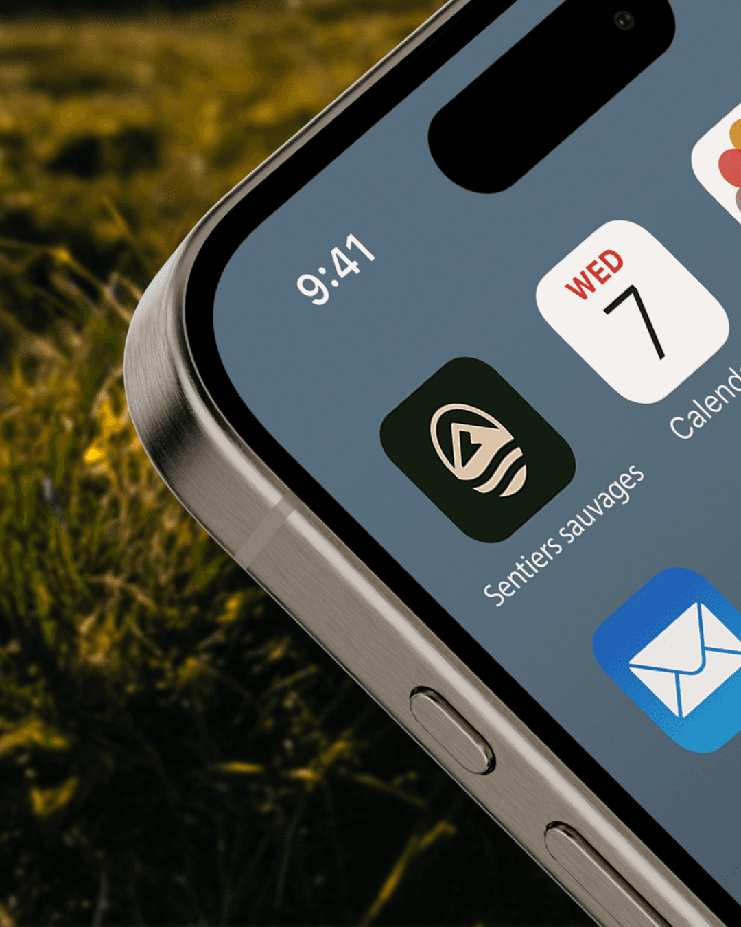 Round black-and-white outdoor sign mounted on a white bracket against a green background, featuring a white globe grid logo on a black face.