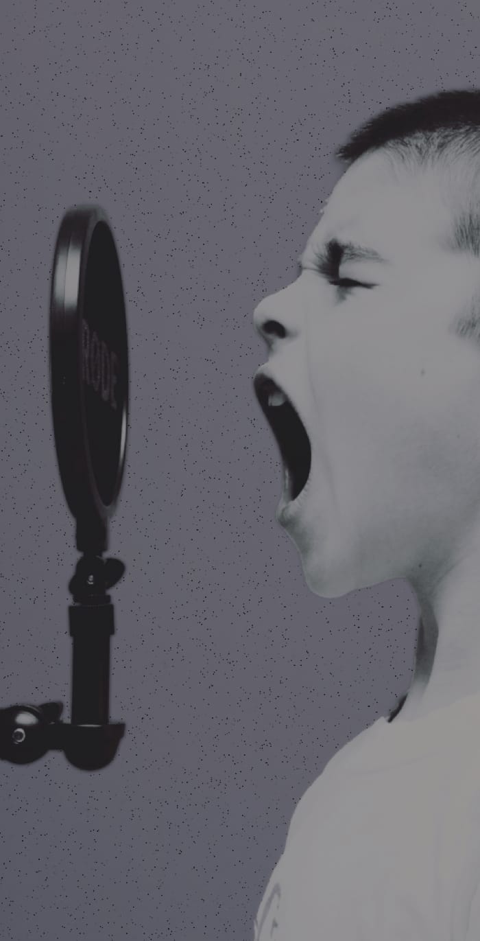 A photo of a young boy shouting into a microphone