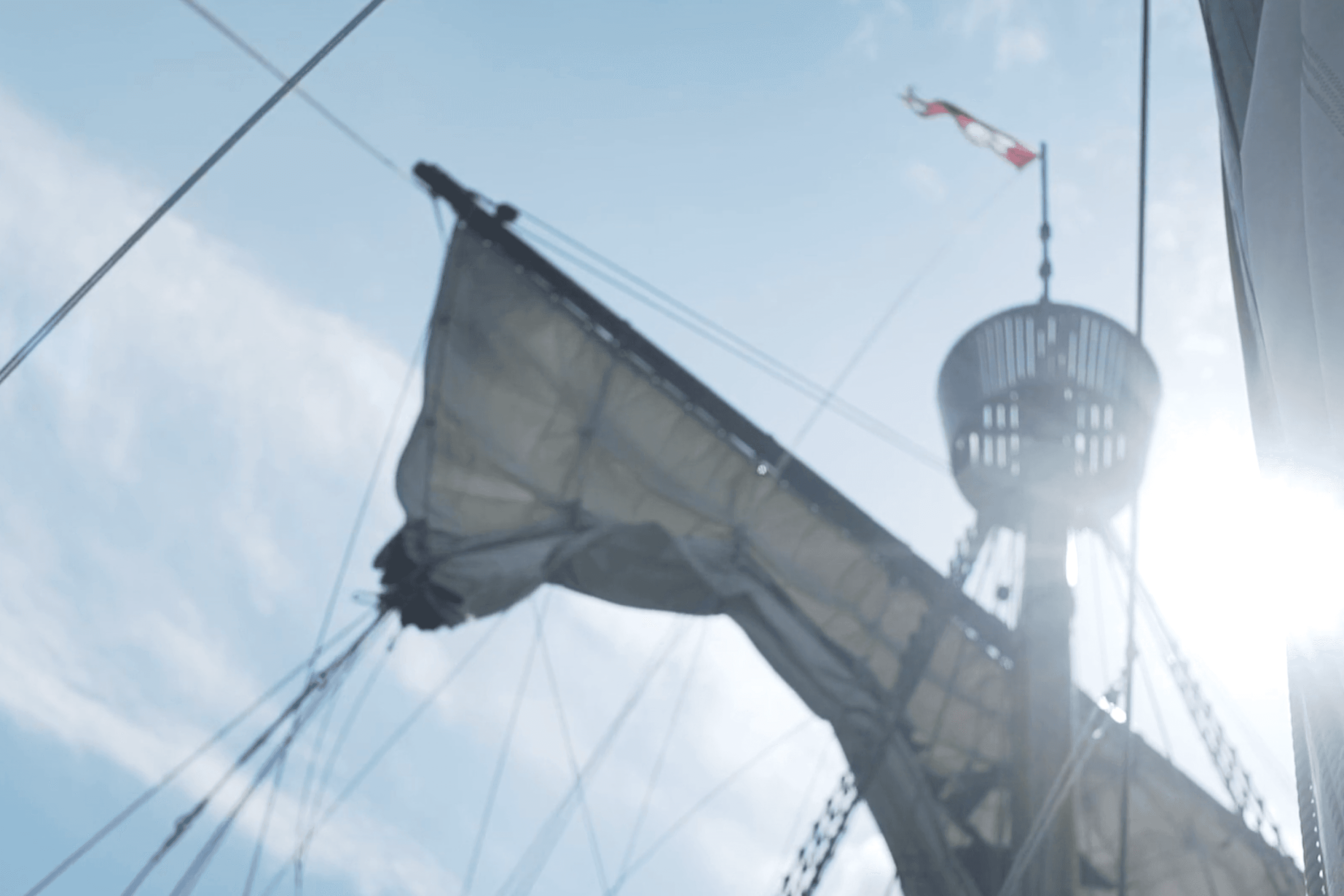 Nautical mast and sail against a bright sky.