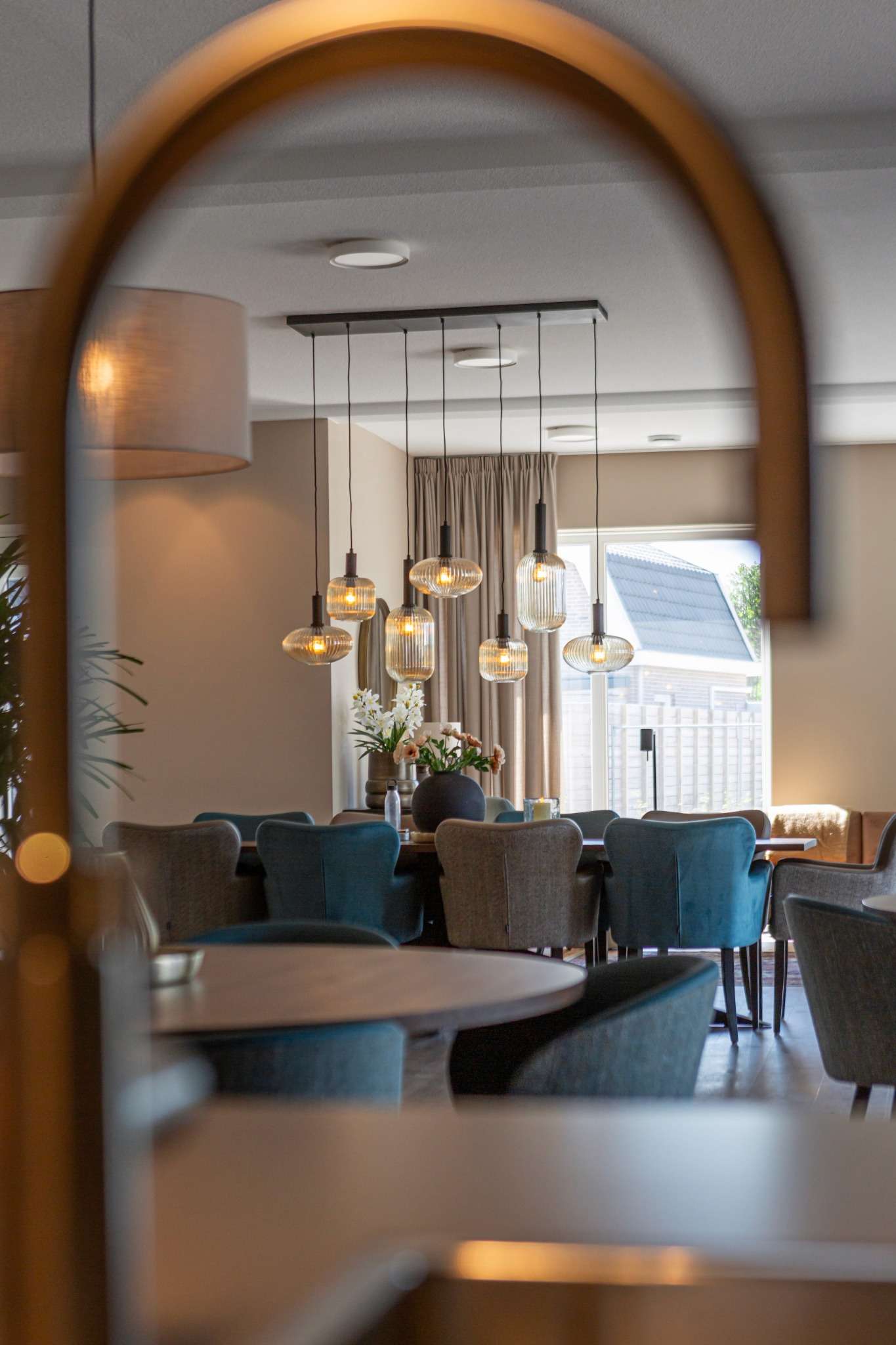 doorkijk woonkeuken ouderenzorg met glaslampen en eetstoelen blauw en taupe