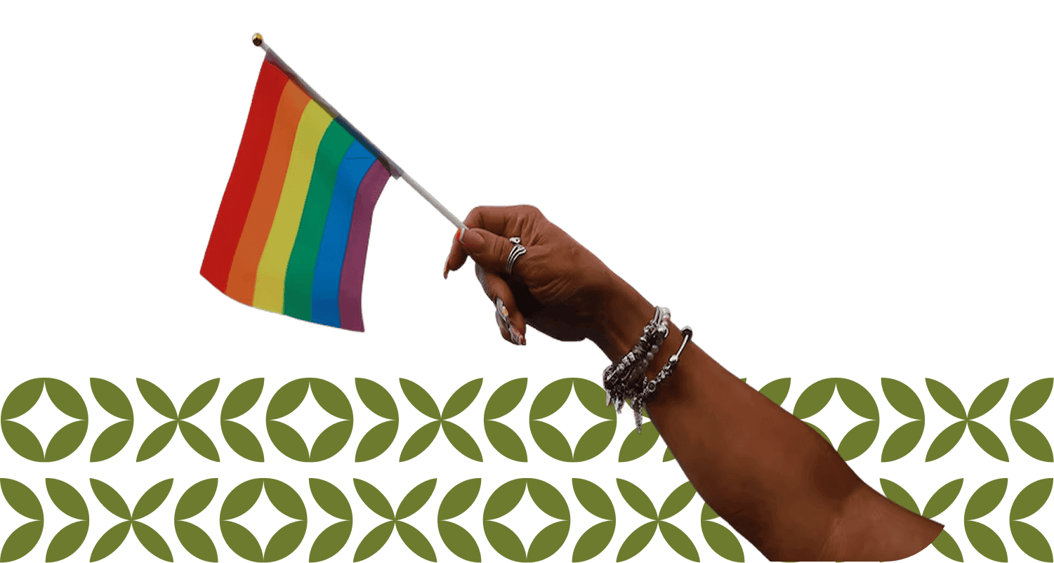 A hand adorned with bracelets confidently holds up a small rainbow flag, symbolizing LGBTQ+ pride and inclusivity, against a background with subtle geometric patterns.