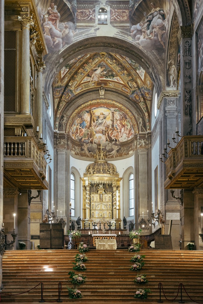 Navata della chiesa con volta affrescata, altare dorato e panche decorate con fiori per la cerimonia matrimoniale
