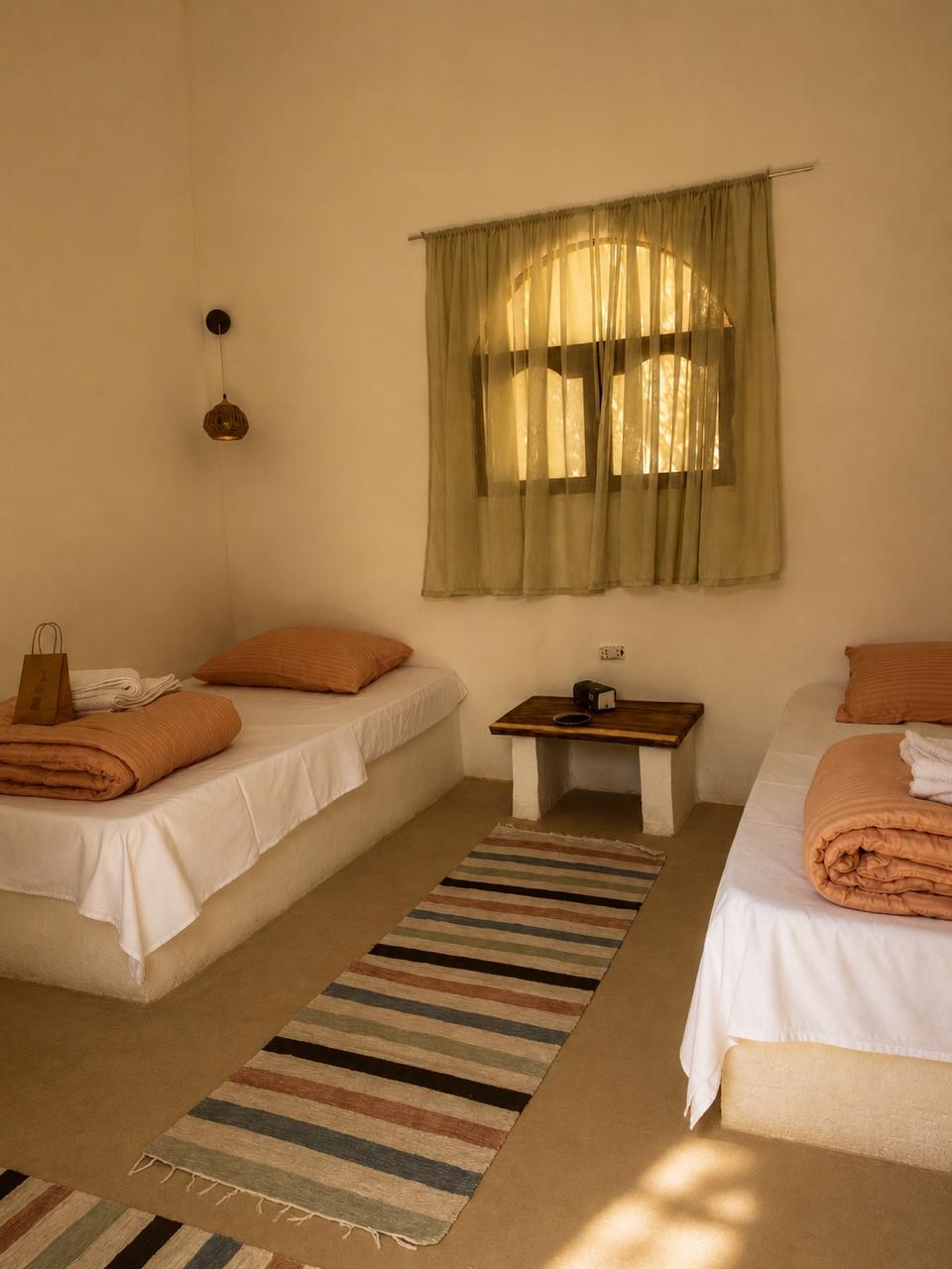 Twin guest bedroom with natural bedding and woven rugs