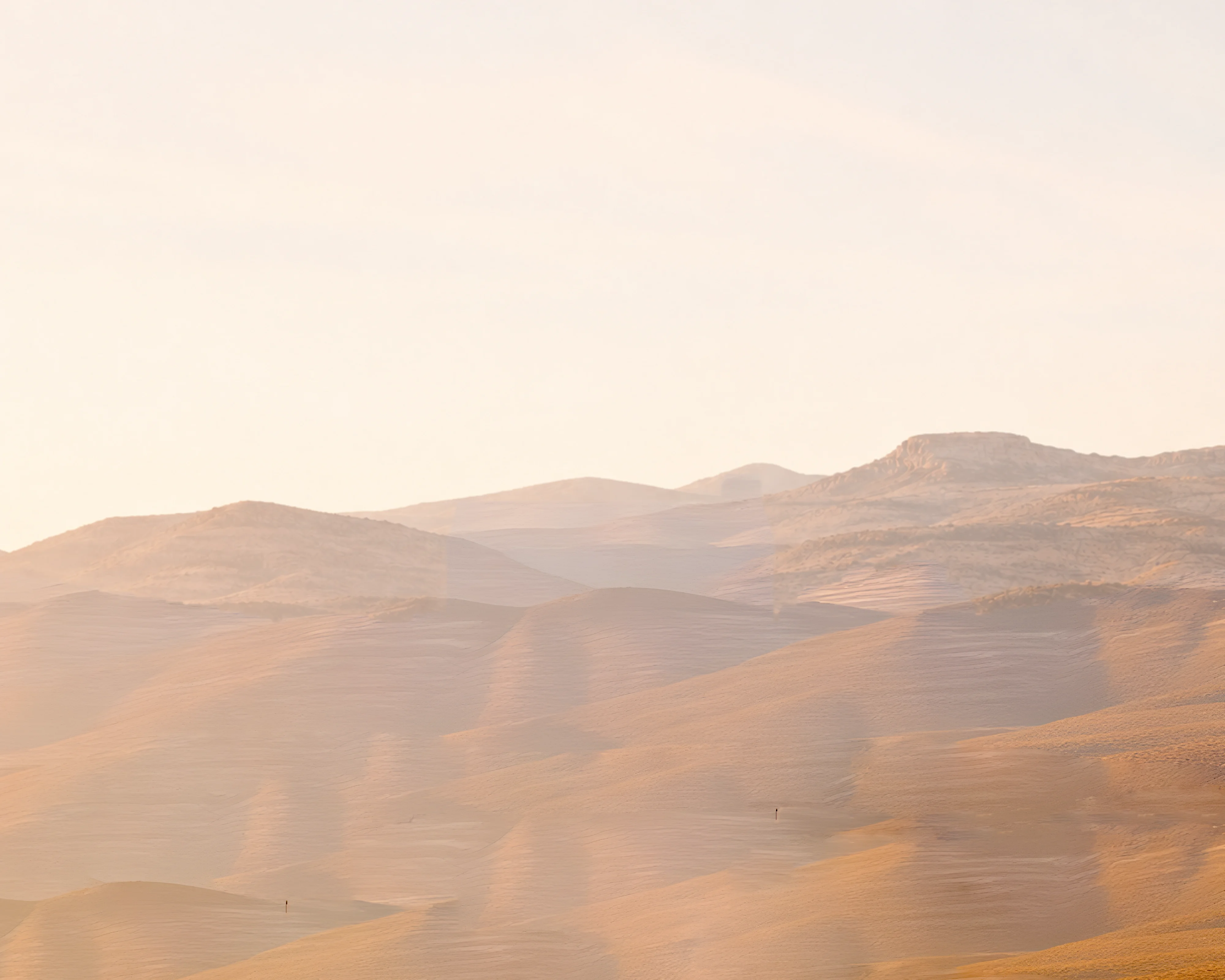 Warm limestone mountains beneath a clear ivory sky