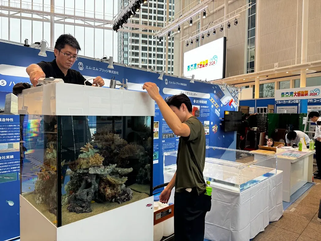 展示会会場で水槽の設営と調整作業を行う専門スタッフ
