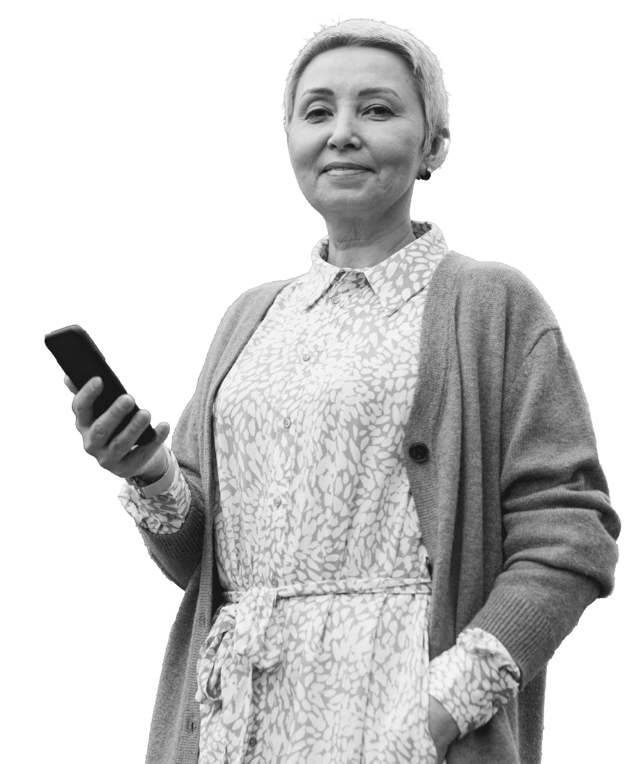 A person in a patterned blouse and cardigan holds a smartphone, set against a plain background, symbolizing connectivity in the context of metals trading.