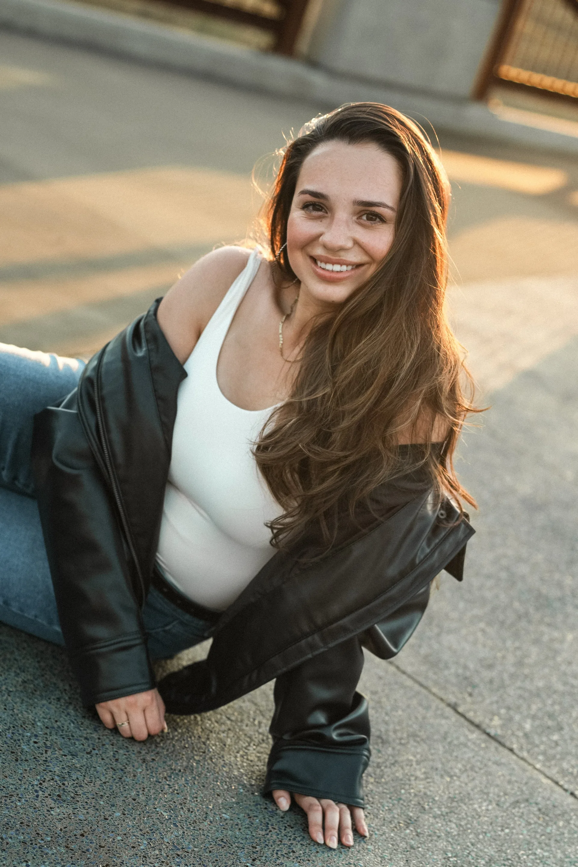 Young woman in a white sweatshirt posing outdoors at golden hour