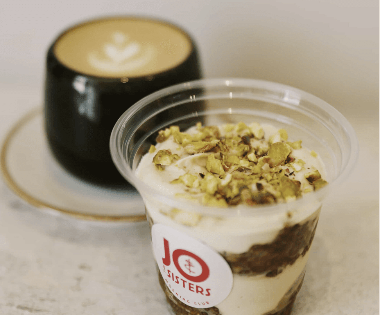 Pistachio dessert cup from Jo & The Sisters Morning Club served with cappuccino on a café table