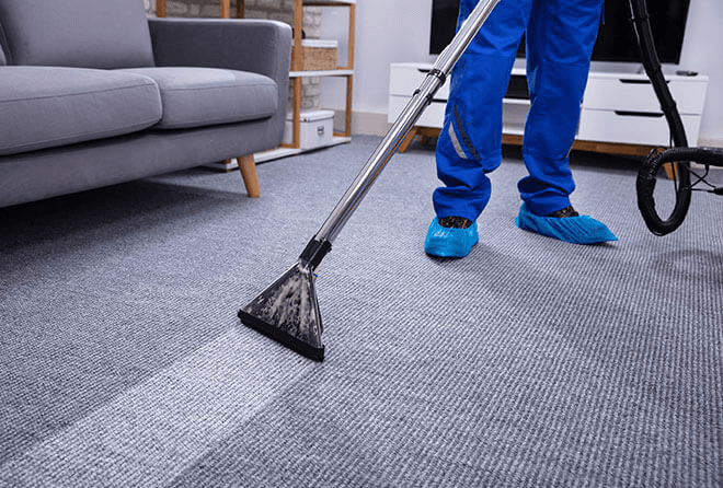 A person in protective suit cleans a carpet.