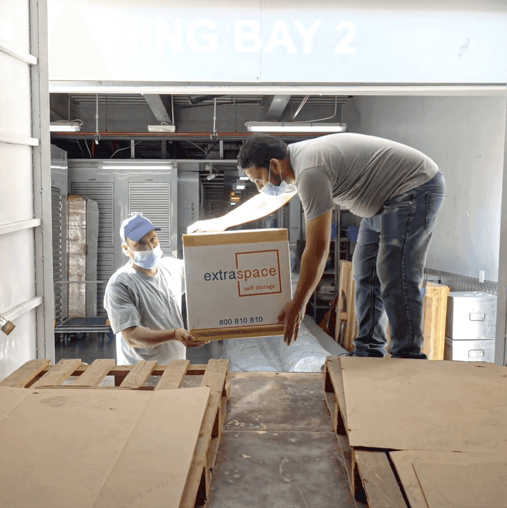 Workers handling Extra Space Self Storage boxes in a loading area.
