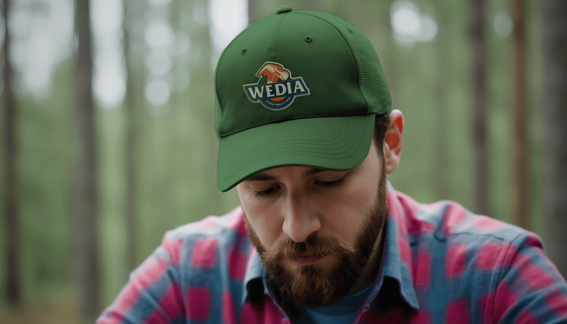 A man wearing a green cap with the WEDIA contracting logo on the front