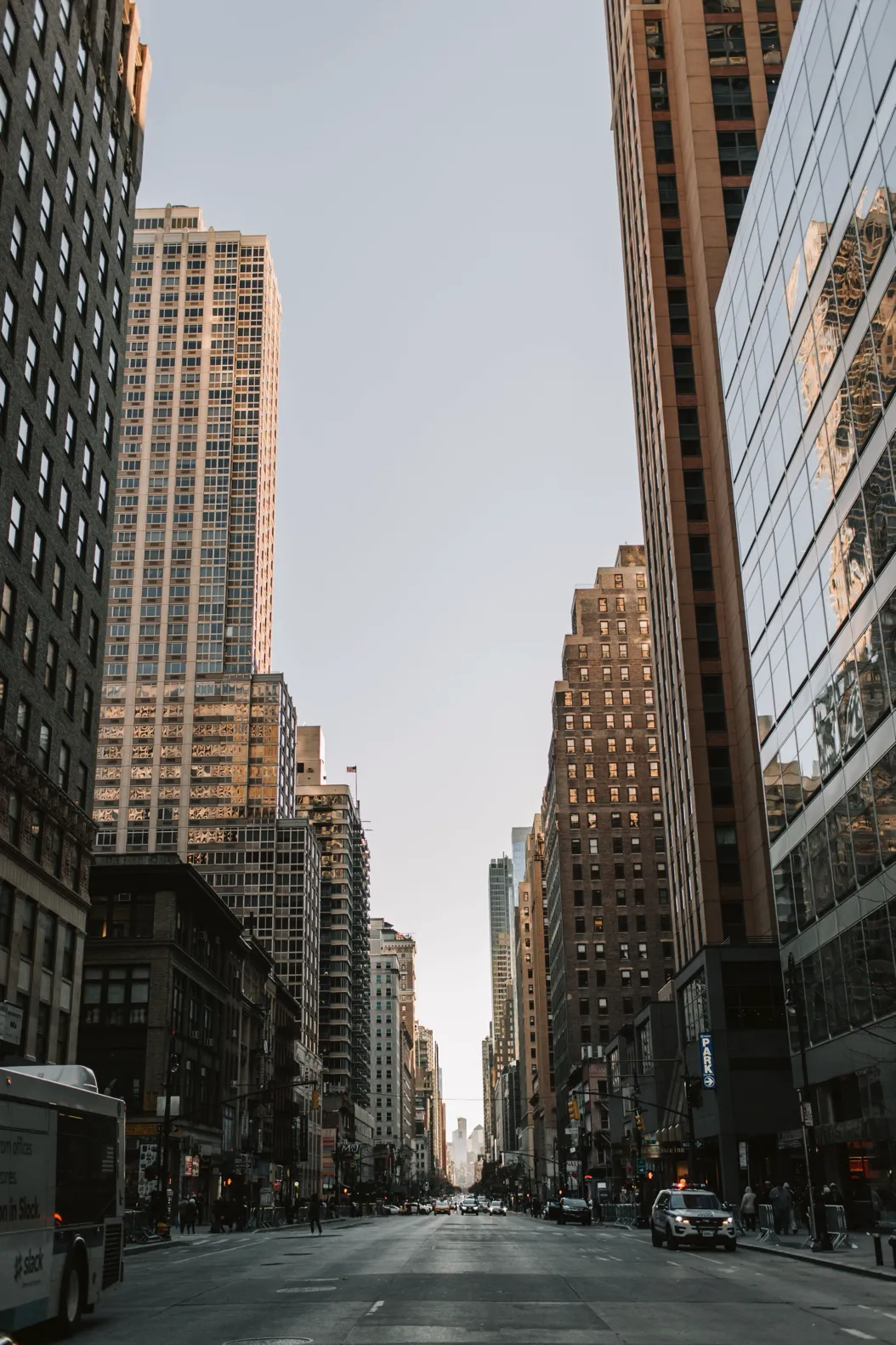 Street-level view of Manhattan skyscrapers framed by historic buildings, with emergency vehicles in the foreground.