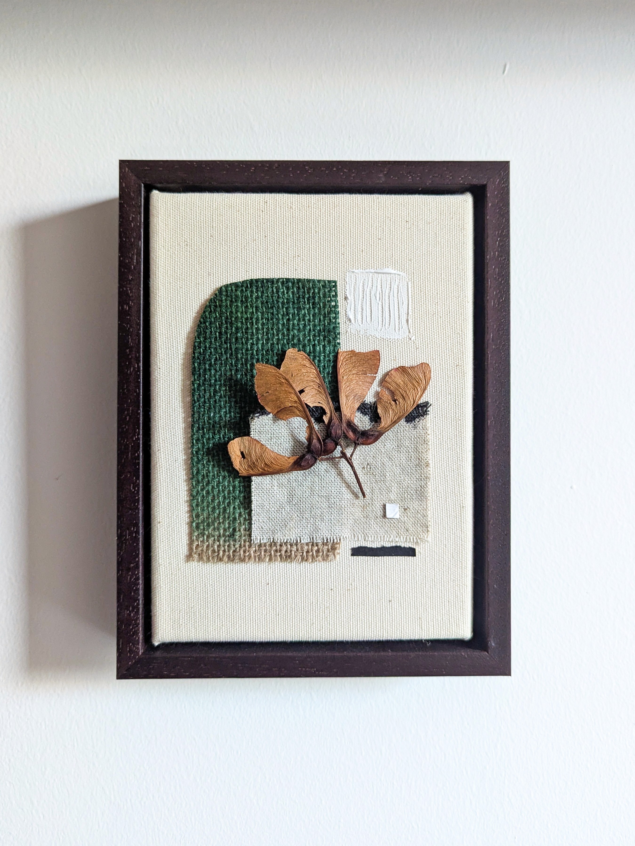 Framed artwork featuring abstract shapes and soft colors, displayed against a light wall backdrop.