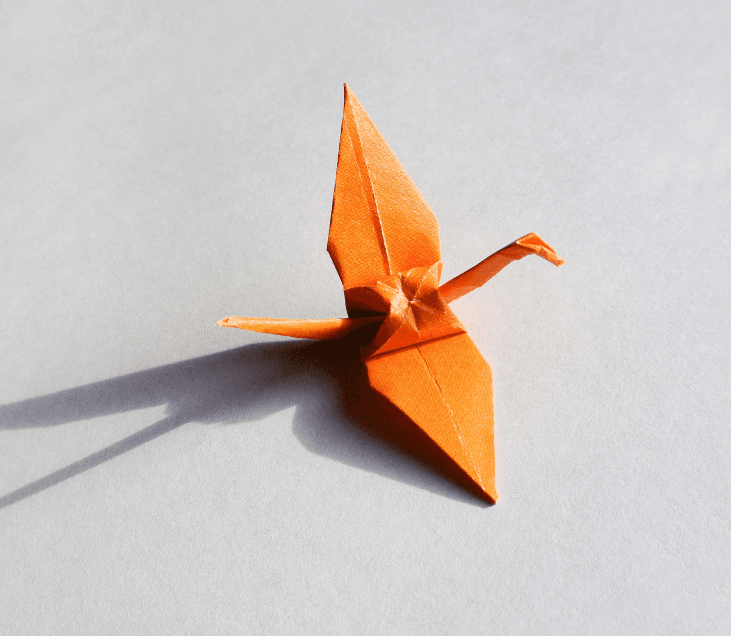 an orange origami bird on a white surface
