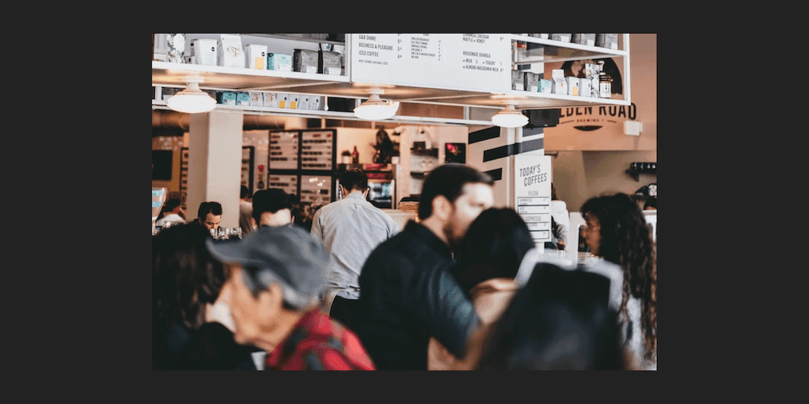 Busy café with customers at a service counter and menu boards on the wall