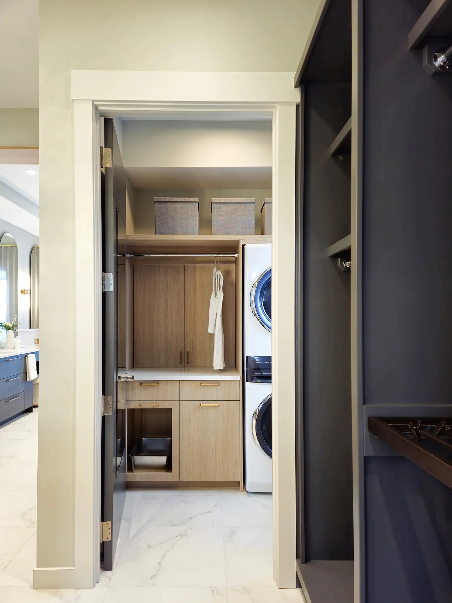Image of laundry closet with stacked laundry and lots of storage in custom light woodwork.