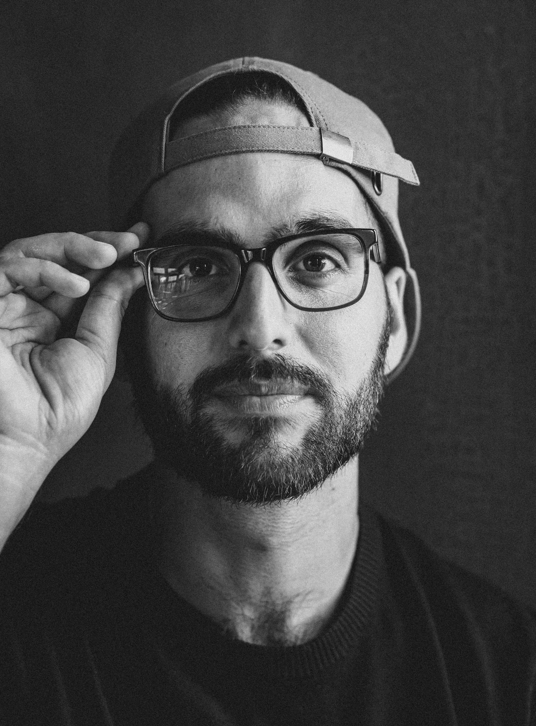 Simone Stolzoff holding his eye glasses, black and white portrait