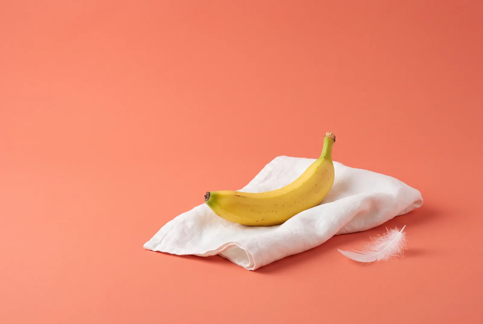 A banana on a soft folded towel with a white feather, a gentle step-by-step death grip recovery plan