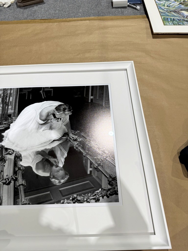 Black-and-white bridal portrait photograph being framed on a work table