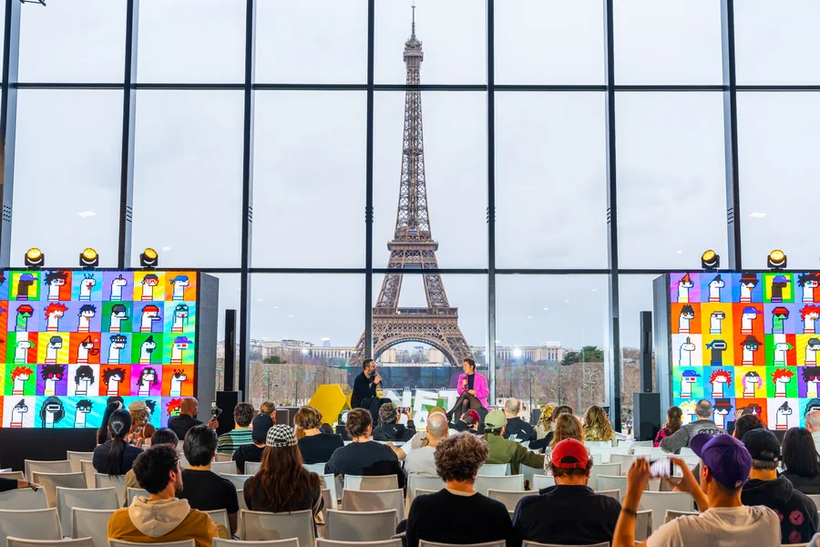Conférence NFT Paris au Grand Palais, avec des intervenants et le public face à la tour Eiffel.